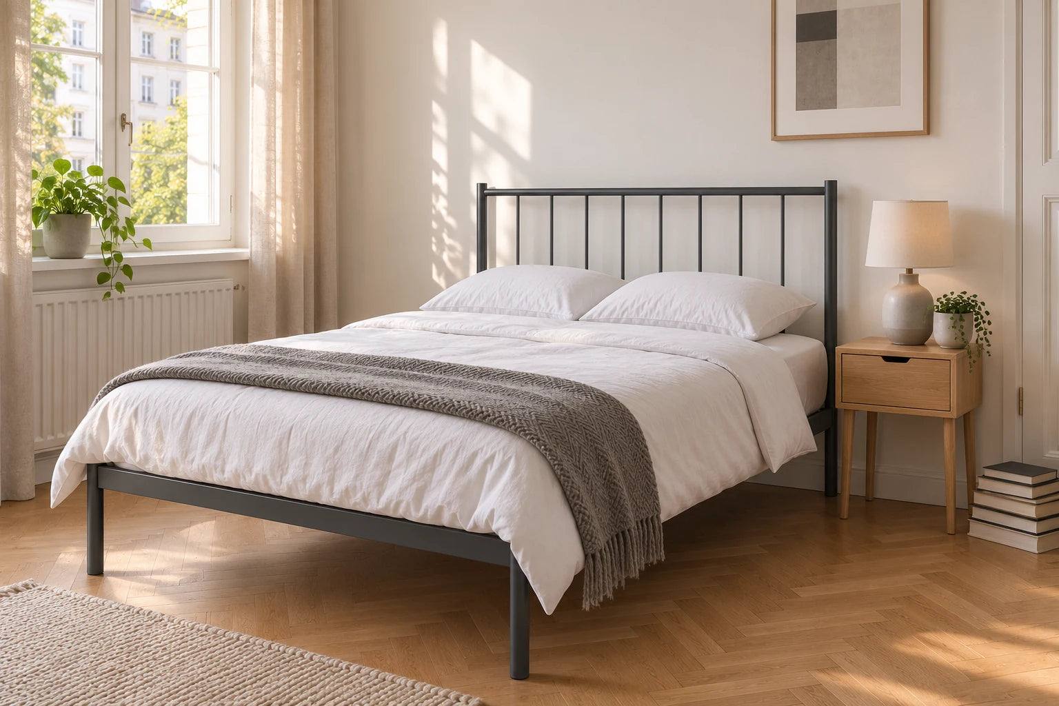 Metallbett 120 x 200 cm in dunkelgrau in einem kompakten Altbau-Schlafzimmer mit Fischgrätparkett, weißer Bettwäsche und minimalistischem Design