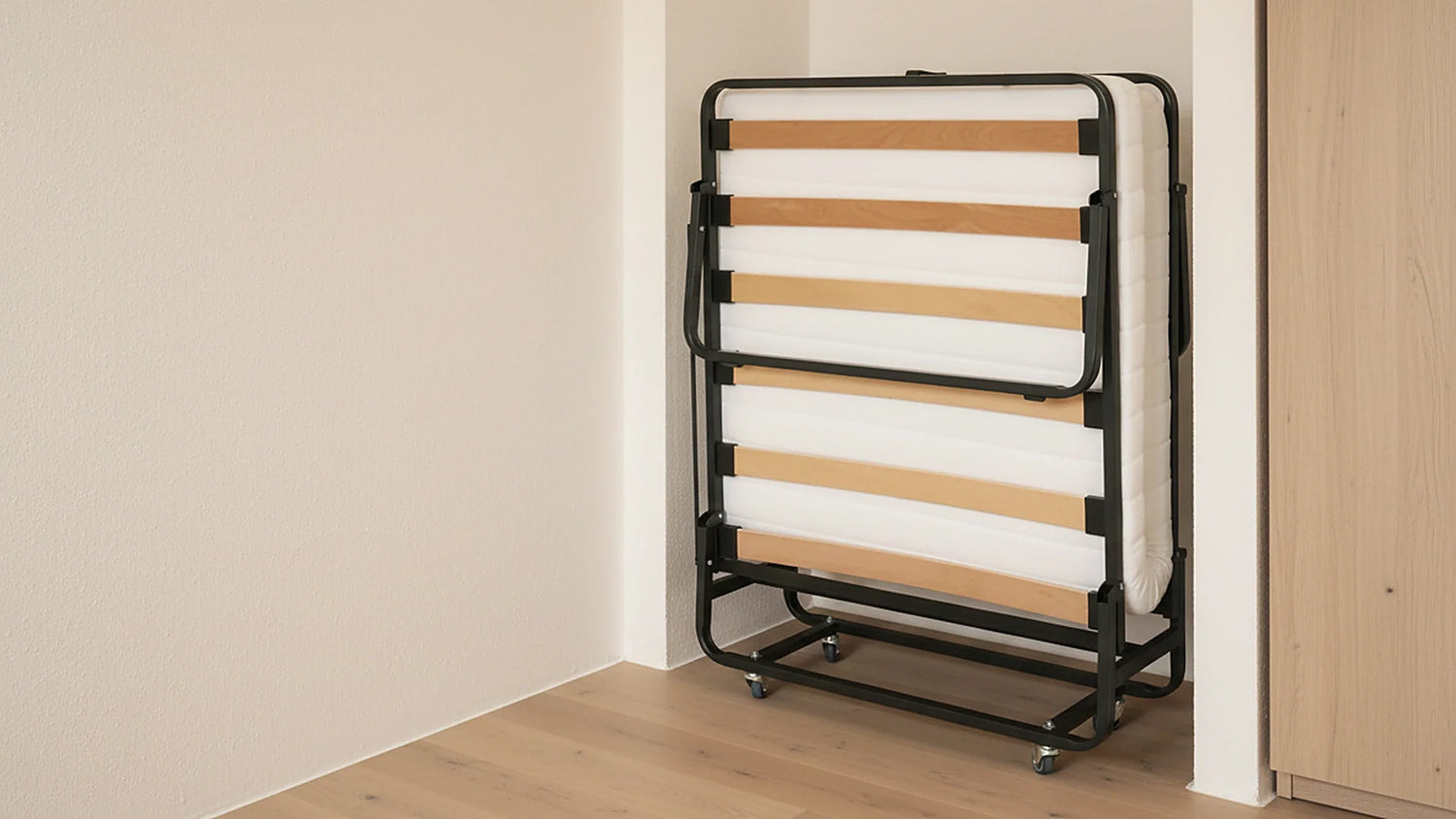 Zusammengeklapptes Gästebett GB110 auf Rollen in einer schmalen Nische neben einem Schrank